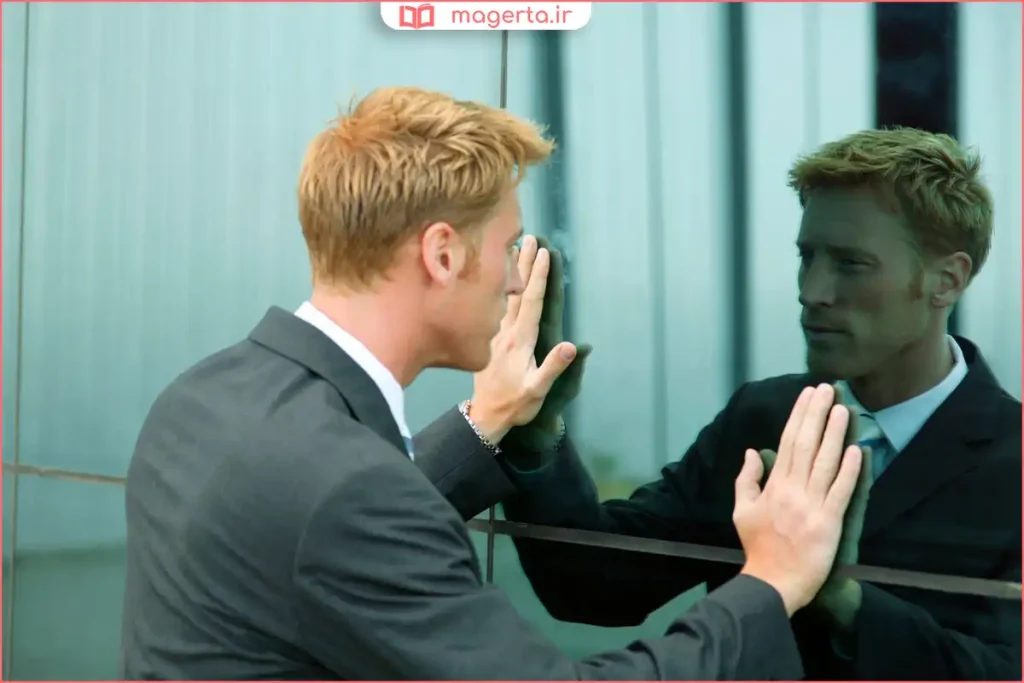 فردی در حال لبخند زدن روبه‌روی آینه و تمرین اعتماد به نفس