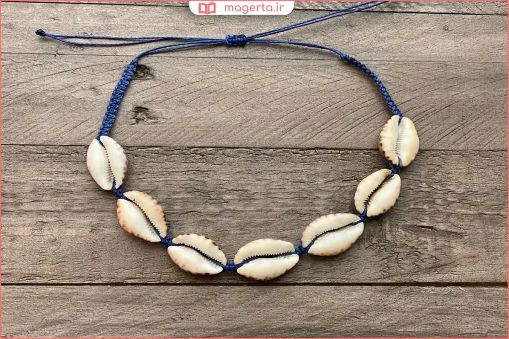 چیدن صدفهای کوچک رنگارنگ روی میز برای ساخت گردنبند دستساز