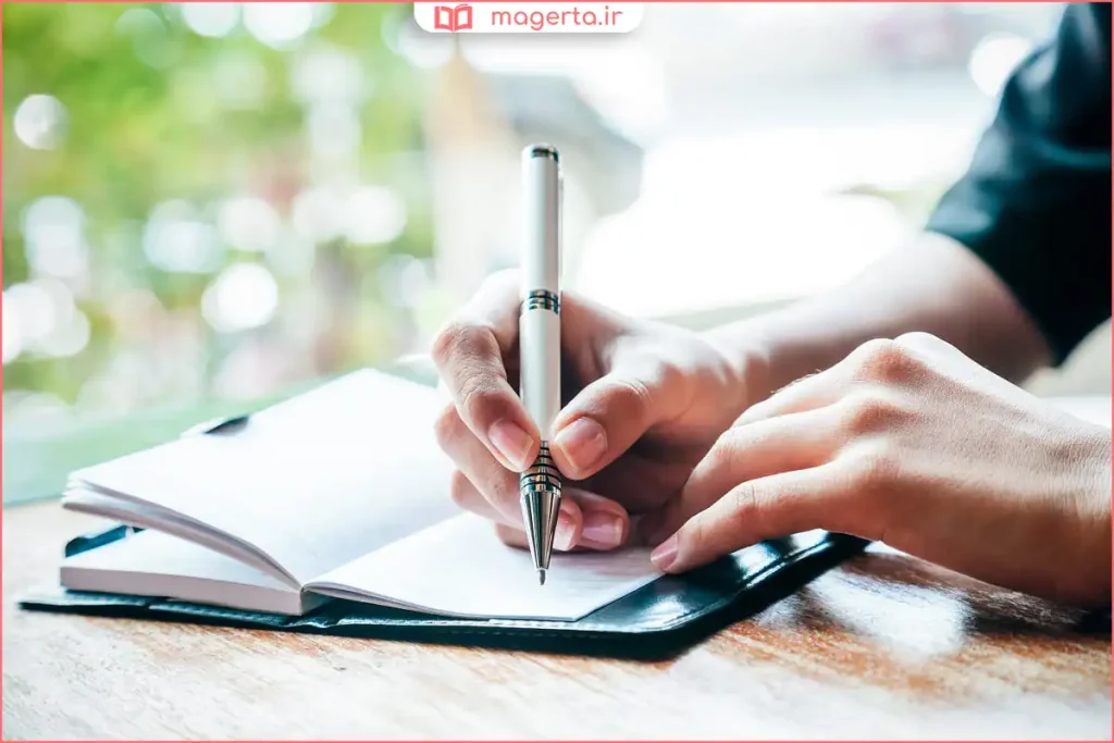 خودکار آبی تیره روی دفتر خط‌دار برای نوشتن جزوه درسی