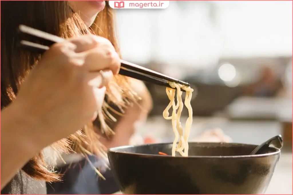 دست در حال گرفتن چاپستیک به‌صورت صحیح برای خوردن غذا