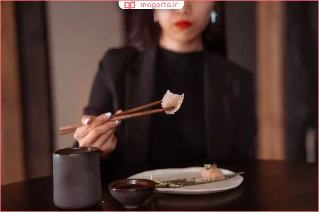 بشقاب سوشی و چاپستیک چوبی کنار ظرف سس سویا