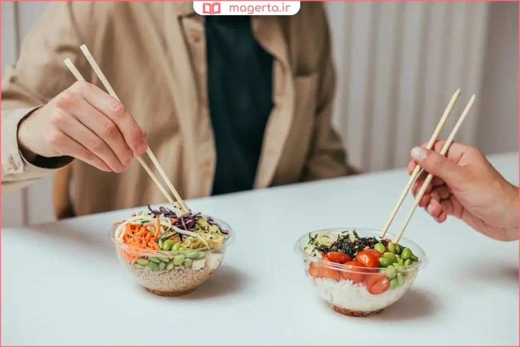 چاپستیک در حال برداشتن تکه نودل از کاسه غذای داغ

