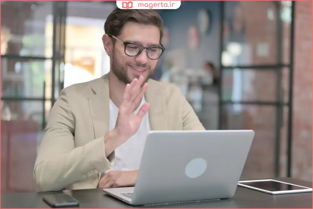 کاربر در حال گرفتن عکس با دوربین وب‌کم لپ‌تاپ روی میز کار