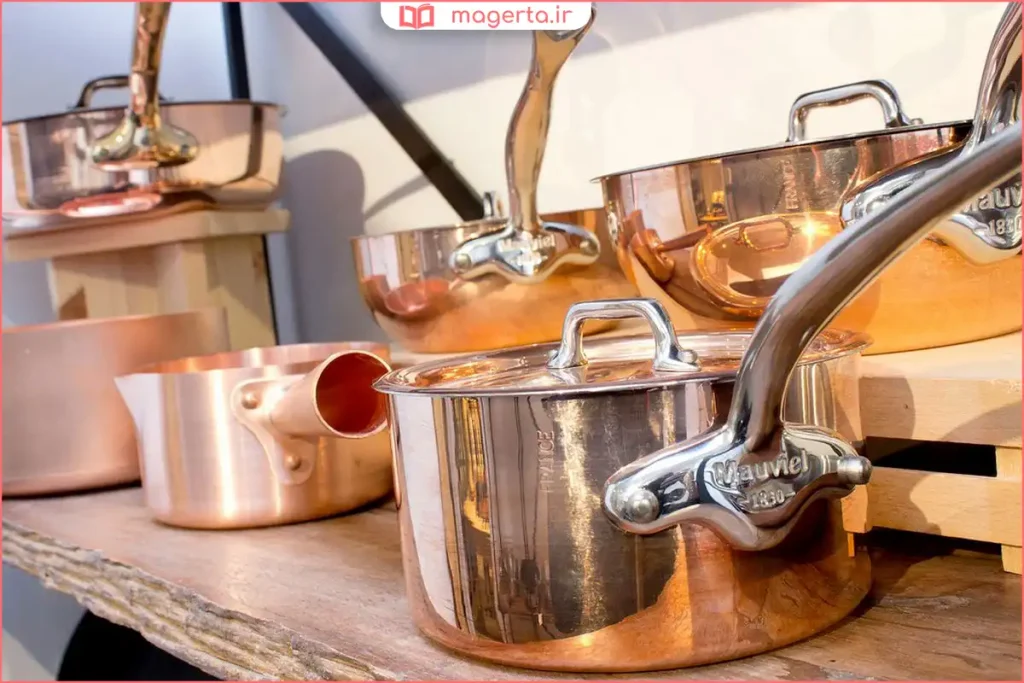 ظروف مسی سنتی با سطح براق روی میز آشپزخانه