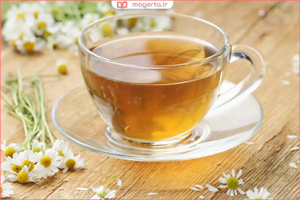 دمنوش بابونه شفاف در لیوان شیشه‌ای روی میز