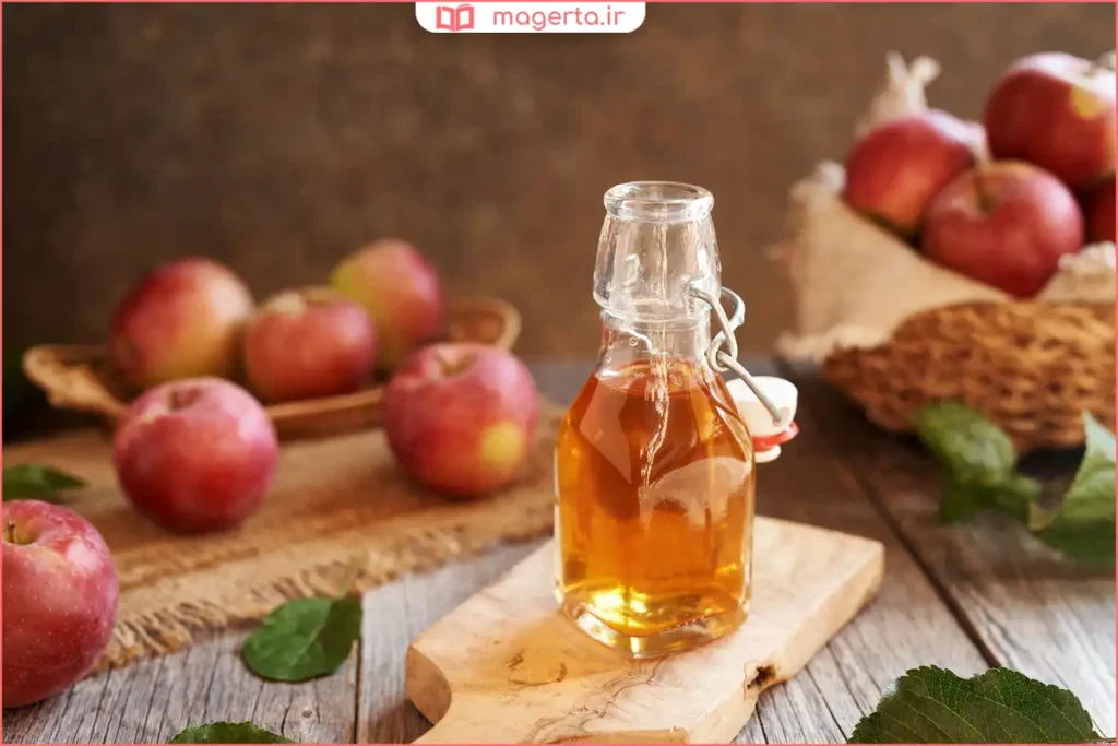 لیوان آب مخلوط با سرکه سیب کنار سیب تازه